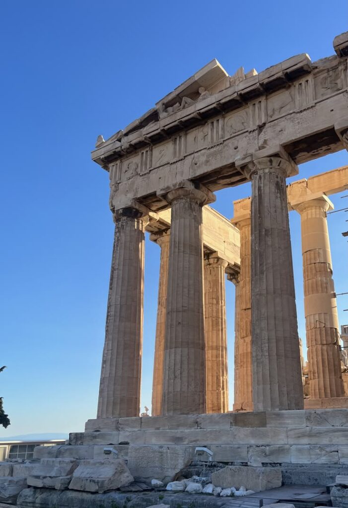 Ancient stone columns of the Acropolis beneath a clear blue sky.